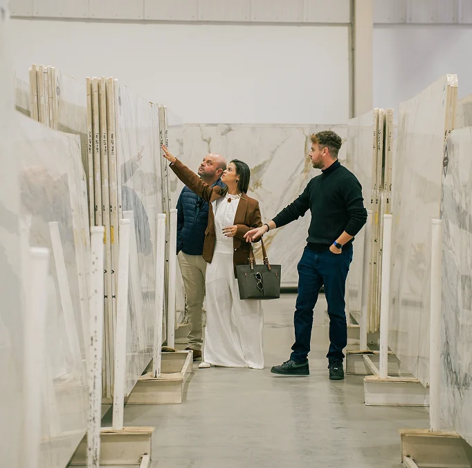 Profissionais e clientes analisam grandes chapas de mármore natural em exposição na Michelangelo.