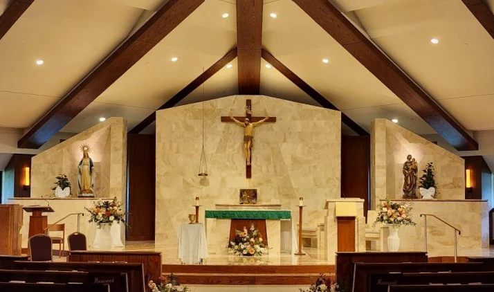 Interior de capela com altar e paredes revestidos com pedra natural clara.